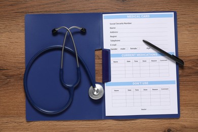 Photo of Medical card form, pen and stethoscope on wooden background, top view