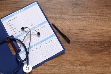 Photo of Medical card form, pen and stethoscope on wooden background, top view. Space for text