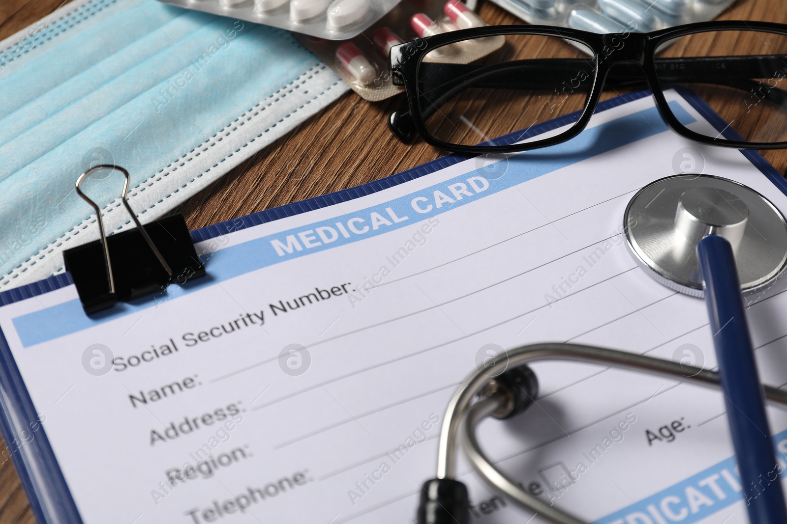 Photo of Composition with medical card form on wooden background, closeup