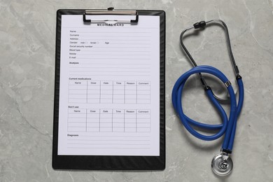 Photo of Medical card form and stethoscope on grey background, top view