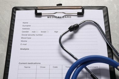 Medical card form and stethoscope on grey background, closeup