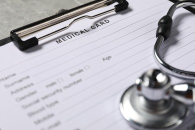 Photo of Medical card form and stethoscope on grey background, closeup