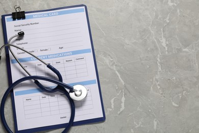 Photo of Medical card form and stethoscope on grey background, top view. Space for text