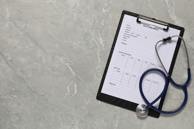 Medical card form and stethoscope on grey background, top view. Space for text