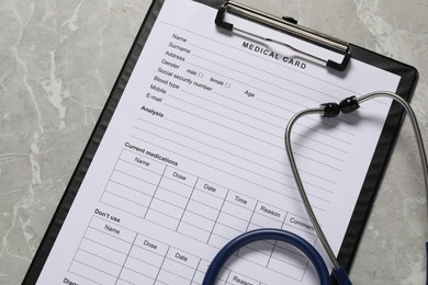 Medical card form and stethoscope on grey background, top view