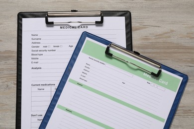 Medical card forms on light wooden background, top view