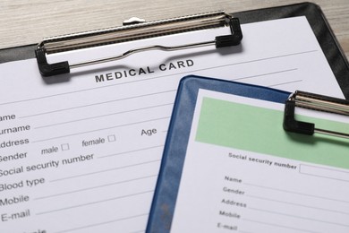 Photo of Medical card forms on light wooden background, closeup