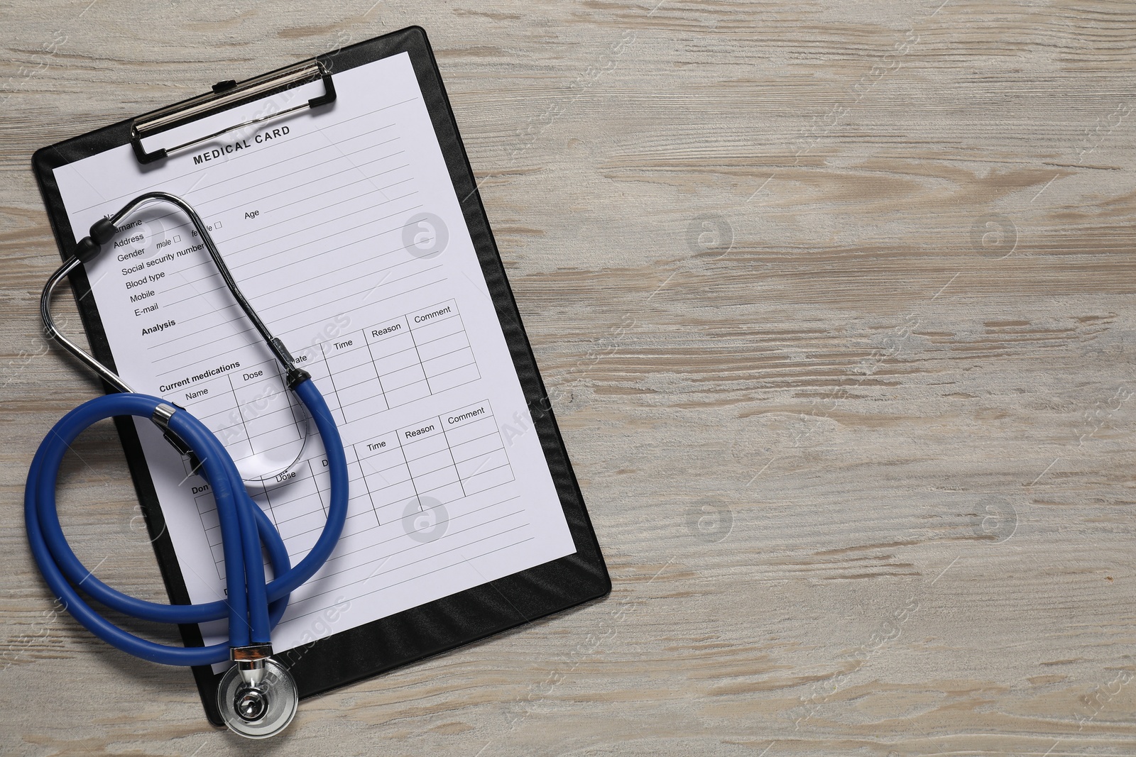 Photo of Medical card form and stethoscope on light wooden background, top view. Space for text