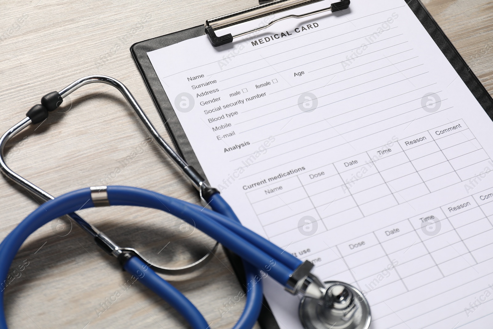 Photo of Medical card form and stethoscope on light wooden background, closeup