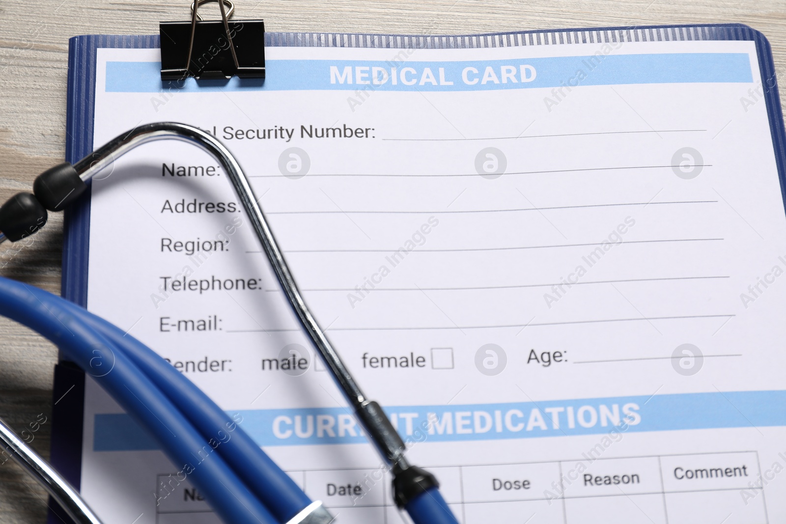 Photo of Medical card form and stethoscope on light wooden background, closeup