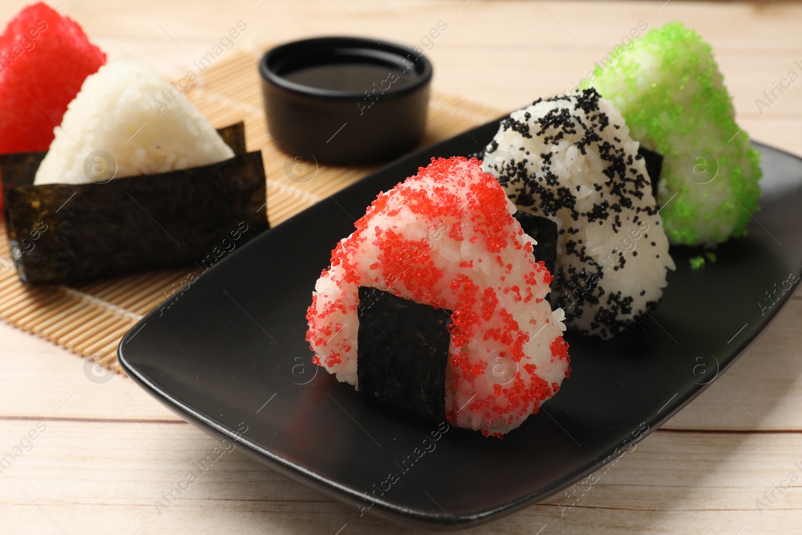 Photo of Tasty tobiko onigiri (Japanese rice balls) served on white wooden table, closeup