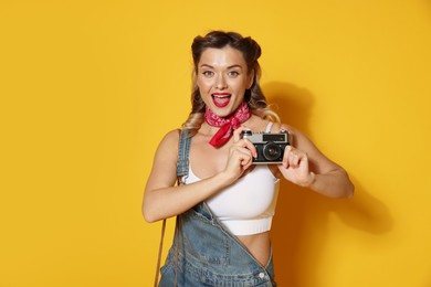 Photo of Beautiful woman with vintage camera on orange background. Pin-up vibes