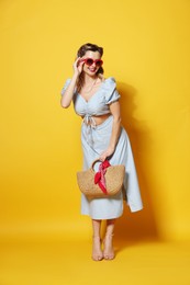 Photo of Happy pin-up woman in sunglasses posing with bag on orange background