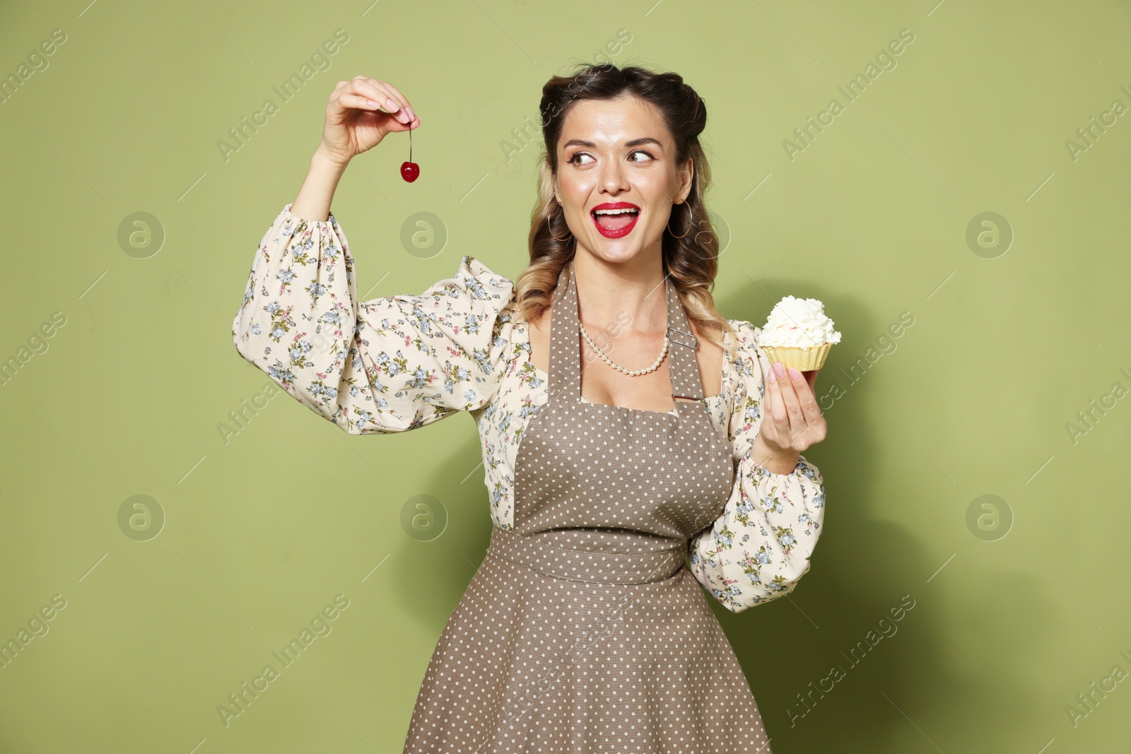 Photo of Happy woman with cupcake and cherry on green background. Pin-up vibe portrait