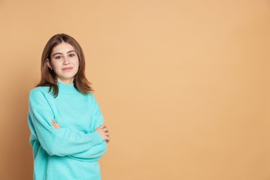 Photo of Portrait of beautiful teenage girl with crossed arms on beige background. Space for text