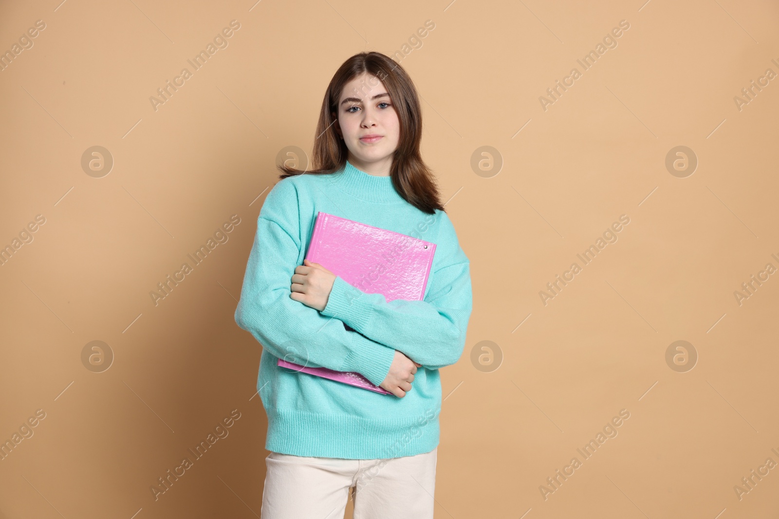 Photo of Portrait of teenage girl with folder on beige background. Space for text