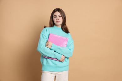 Photo of Portrait of teenage girl with folder on beige background. Space for text