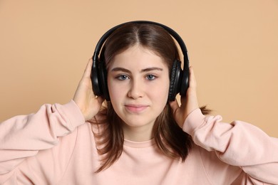 Photo of Portrait of teenage girl in headphones listening to music on beige background