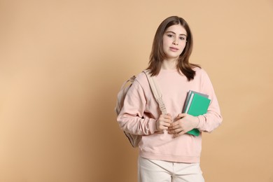 Photo of Portrait of teenage girl with books and backpack on beige background. Space for text