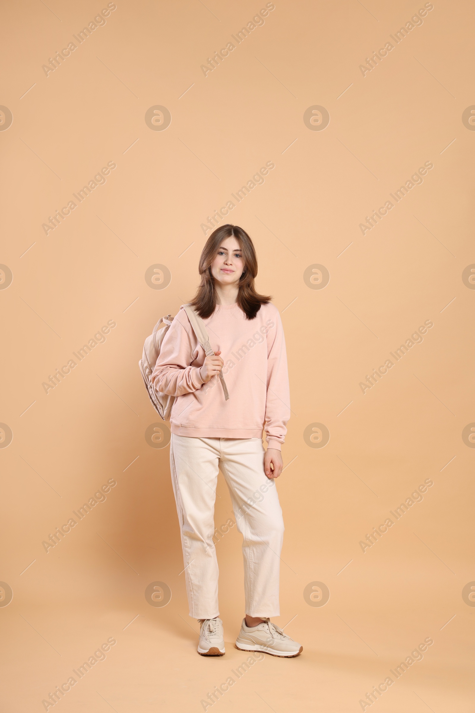 Photo of Portrait of teenage girl with backpack on beige background