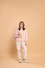 Photo of Portrait of teenage girl with backpack on beige background