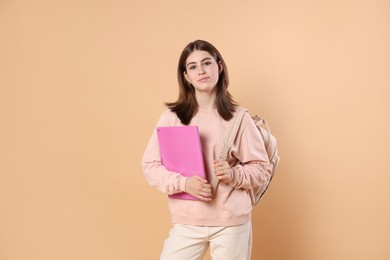 Photo of Portrait of teenage girl with backpack and folder on beige background