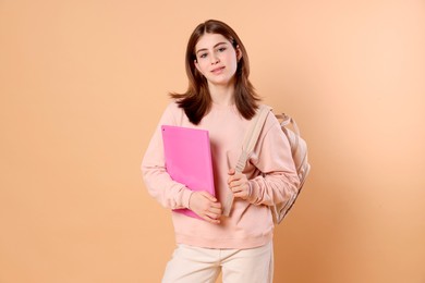 Photo of Portrait of teenage girl with backpack and folder on beige background