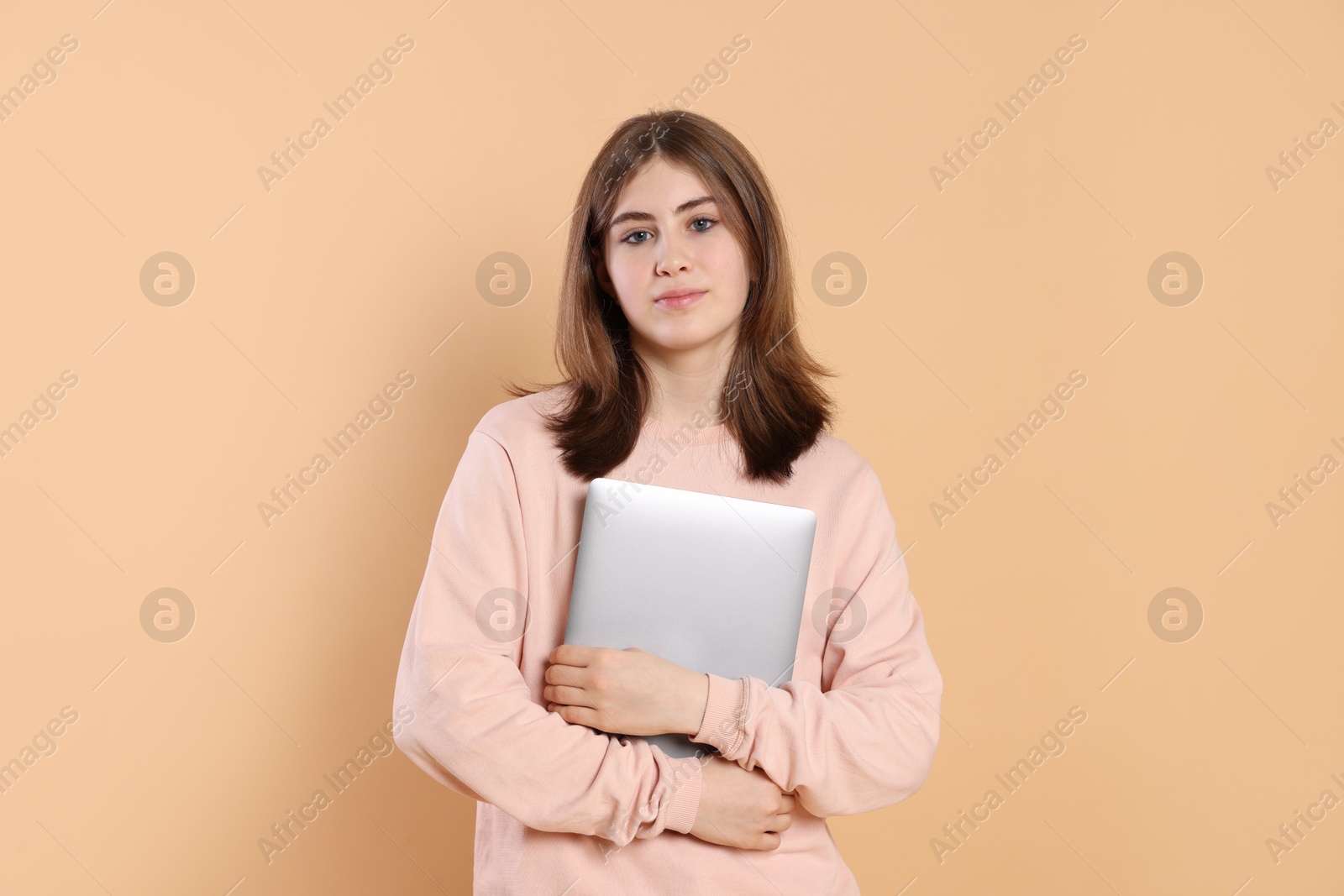 Photo of Portrait of teenage girl with laptop on beige background