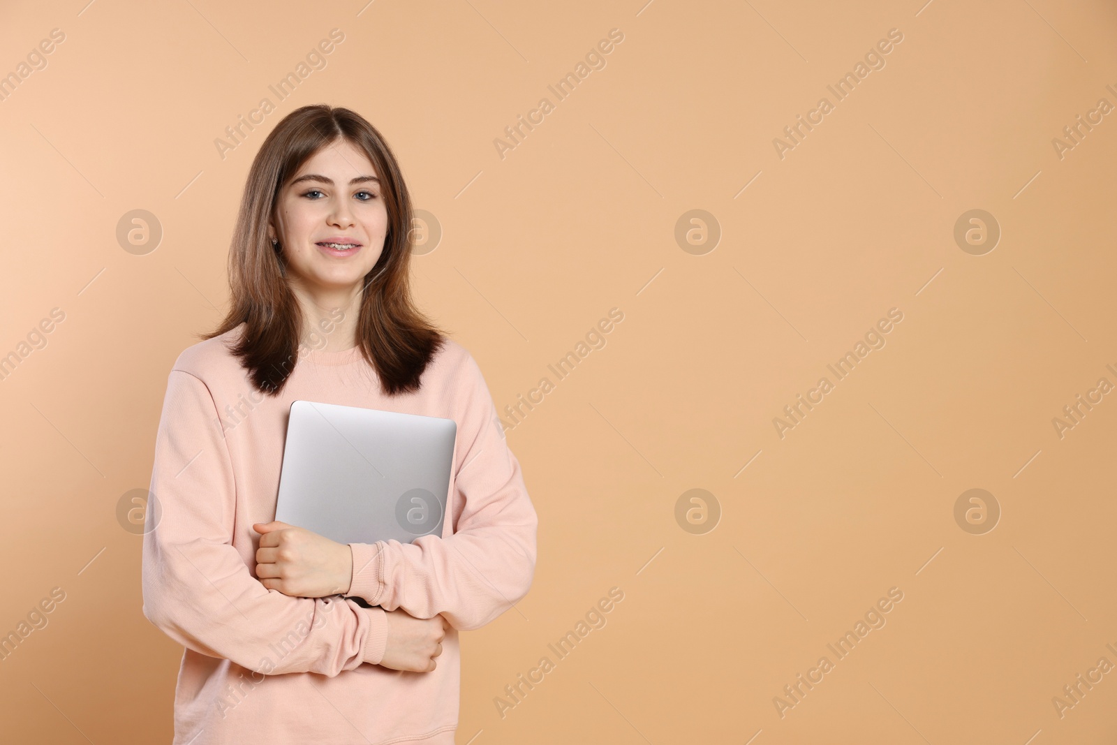 Photo of Portrait of teenage girl with laptop on beige background. Space for text