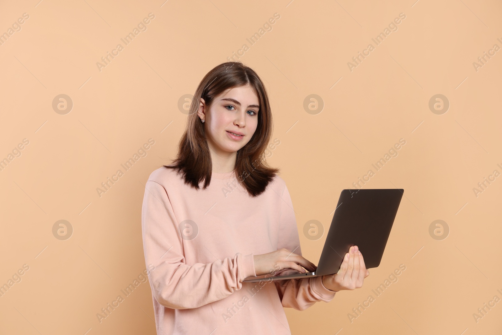 Photo of Portrait of teenage girl using laptop on beige background