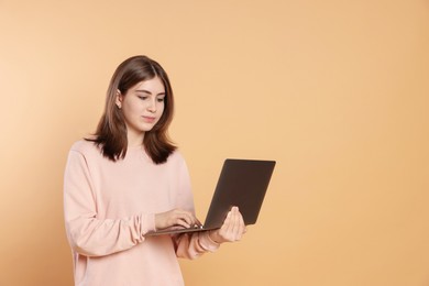 Photo of Portrait of teenage girl using laptop on beige background. Space for text