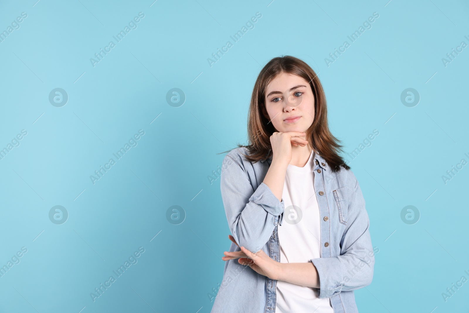 Photo of Portrait of beautiful teenage girl on light blue background. Space for text