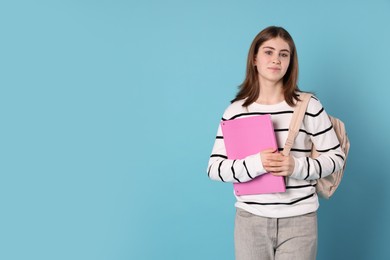 Photo of Portrait of teenage girl with backpack and folder on light blue background. Space for text