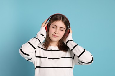 Photo of Portrait of teenage girl in headphones listening to music on light blue background