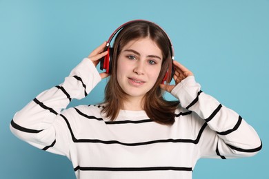 Photo of Portrait of teenage girl in headphones listening to music on light blue background