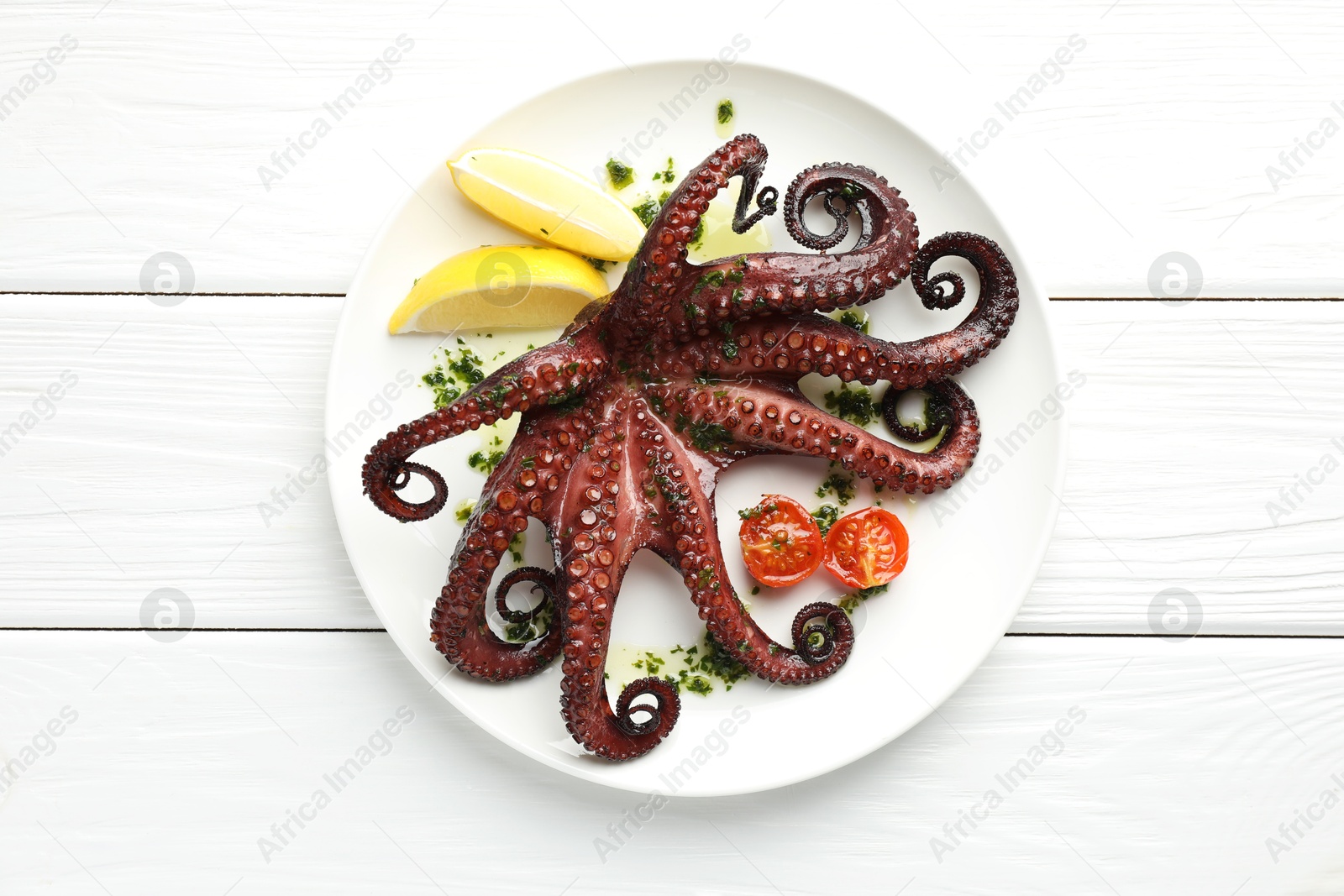 Fried octopus with herb sauce, lemon and tomatoes on white wooden table, top view Photo of Fried octopus with herb sauce, lemon and tomatoes on white wooden table, top view