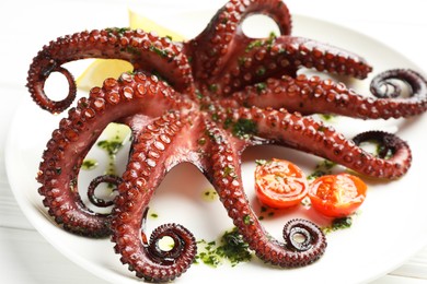 Photo of Fried octopus with herb sauce and tomatoes on white wooden table, closeup