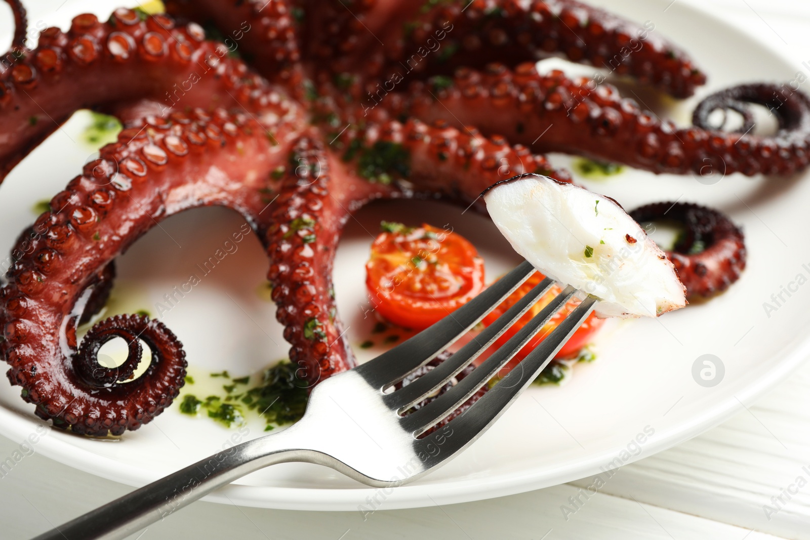 Eating tasty fried octopus with herb sauce at white wooden table, closeup Photo of Eating tasty fried octopus with herb sauce at white wooden table, closeup