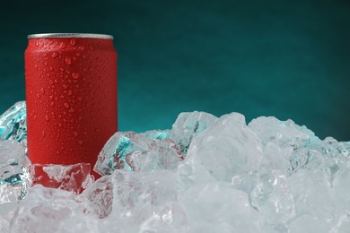 Photo of Refreshing drink in can on ice cubes against teal background, closeup
