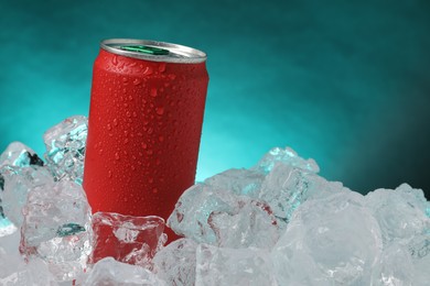 Photo of Refreshing drink in can on ice cubes against teal background, closeup