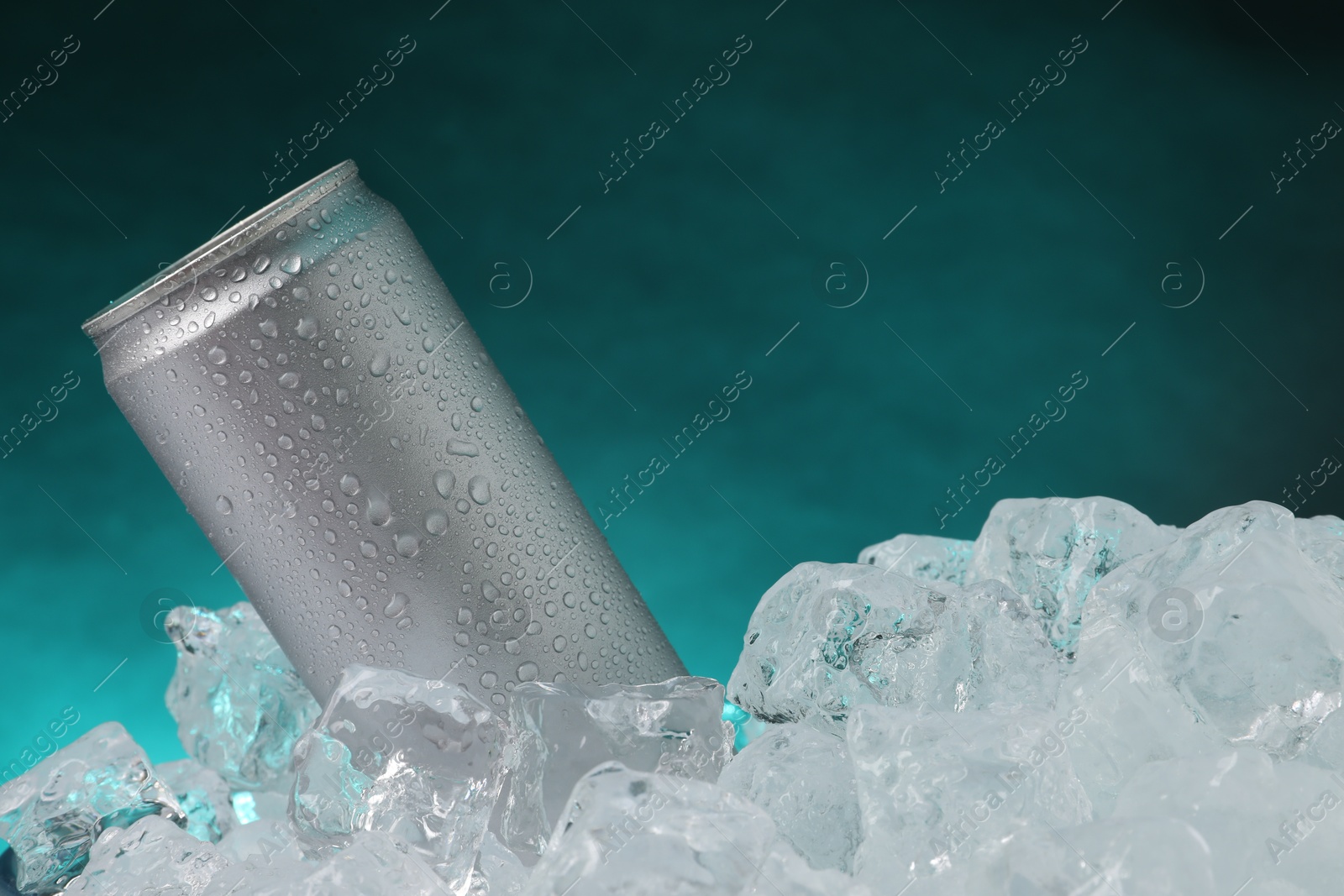 Refreshing drink in can on ice cubes against teal background, closeup Photo of Refreshing drink in can on ice cubes against teal background, closeup