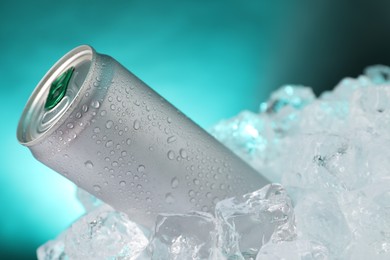 Photo of Refreshing drink in can on ice cubes against teal background, closeup