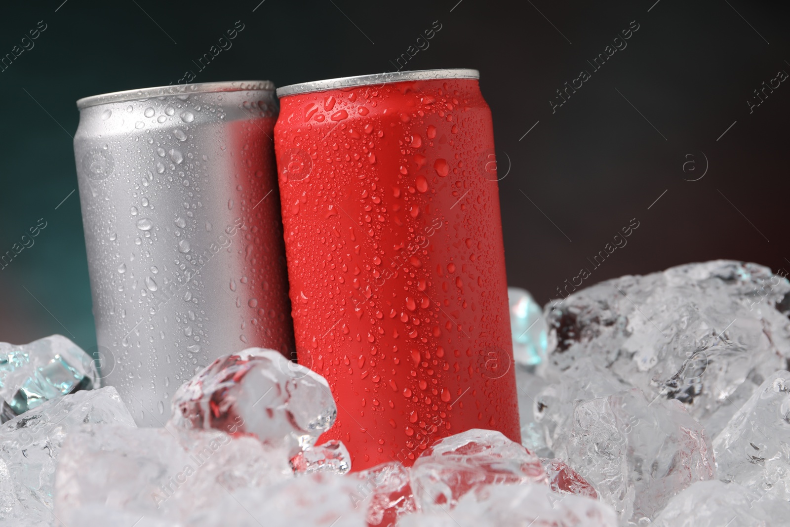 Refreshing drinks in cans on ice cubes against dark background, closeup Photo of Refreshing drinks in cans on ice cubes against dark background, closeup