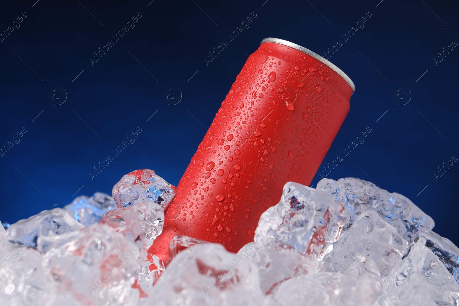 Refreshing drink in can on ice cubes against dark blue background Photo of Refreshing drink in can on ice cubes against dark blue background