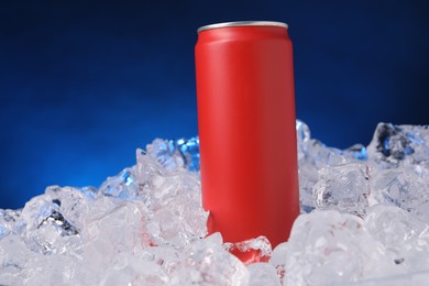 Photo of Refreshing drink in can on ice cubes against dark blue background