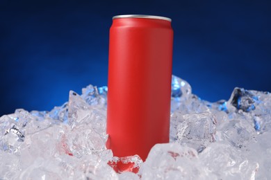 Photo of Refreshing drink in can on ice cubes against dark blue background