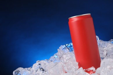 Photo of Refreshing drink in can on ice cubes against dark blue background