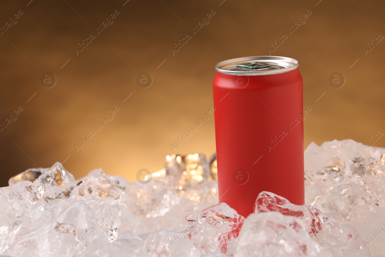 Refreshing drink in can on ice cubes against golden background, closeup Photo of Refreshing drink in can on ice cubes against golden background, closeup