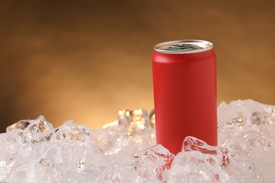 Photo of Refreshing drink in can on ice cubes against golden background, closeup
