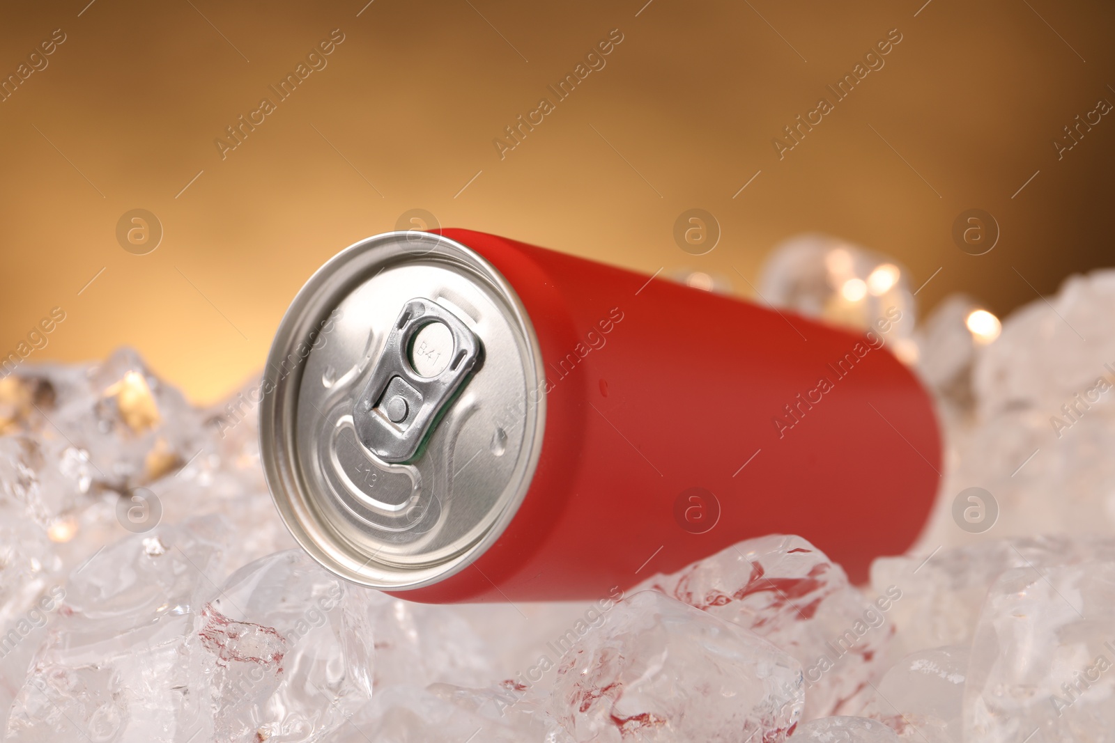 Refreshing drink in can on ice cubes against golden background, closeup Photo of Refreshing drink in can on ice cubes against golden background, closeup